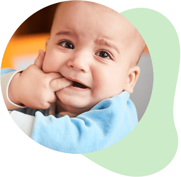 Baby sticks fingers in their mouth and frowns because of teething discomfort.