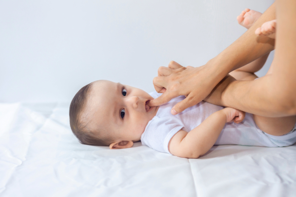 Mother applying Orajel Baby teething gel to infant's gums.