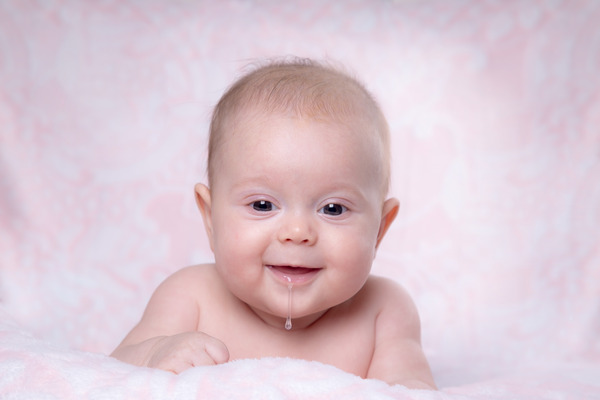 Baby smiling with drool coming out of their mouth.